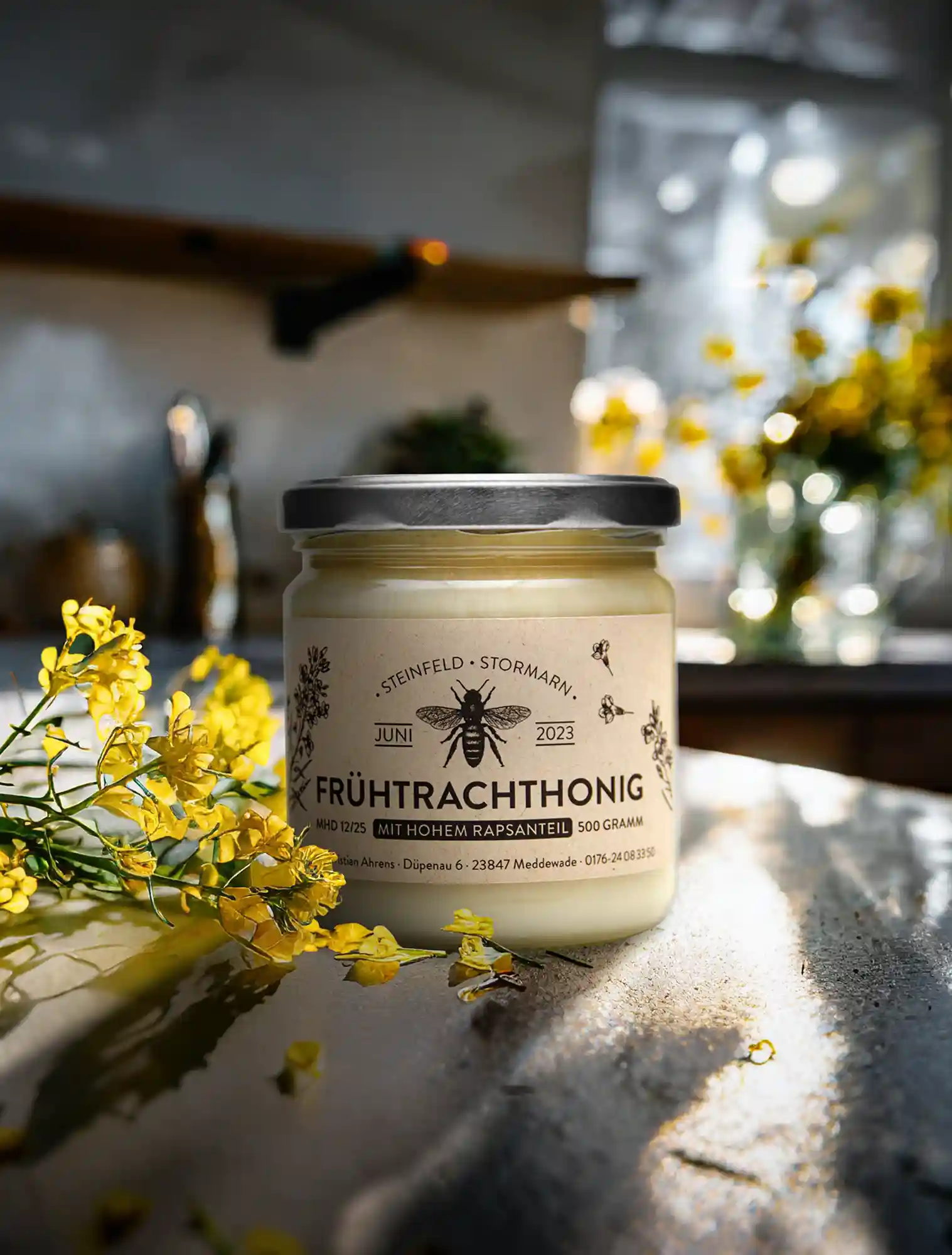 Honigglas auf in einer modernen sonnigen Küche daneben Rapsblüten