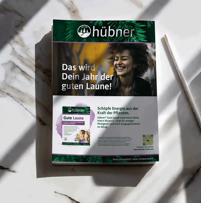 Hübner Gute Laune Werbeanzeige Hübner Naturarzneimittel Hersteller Re-Design und Marken Kommunikation. Eine Werbeanzeige für das Produkt gute Laune. Oben In einem grünen Streifen mit einem Tannen-Hintergrund groß das Logo. Darunter ein Bild einer lachenden farbigen Frau scharf im Hintergrund eine mit Graffiti bemalten Wand. Auf dem Bild die Headline: Das wird dein Jahr der guten Laune. Unter dem Bild ist eine weiße Fläche auf der das Produkt abgebildet ist . Da neben steht: Schöpfe Energie aus der Kraft der Natur