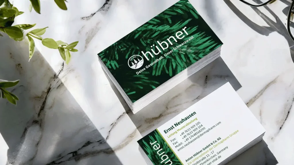 Re-Design Corporate von Hübner Naturarzneimittel Re-Design des Corporate Design von Hübner Naturarzneimittel. Zwei Stapel Visitenkarten vorne groß das neue Logo der Marke auf dunkel Grünem Hintergrund hinten die Daten der Mitarbeiter.