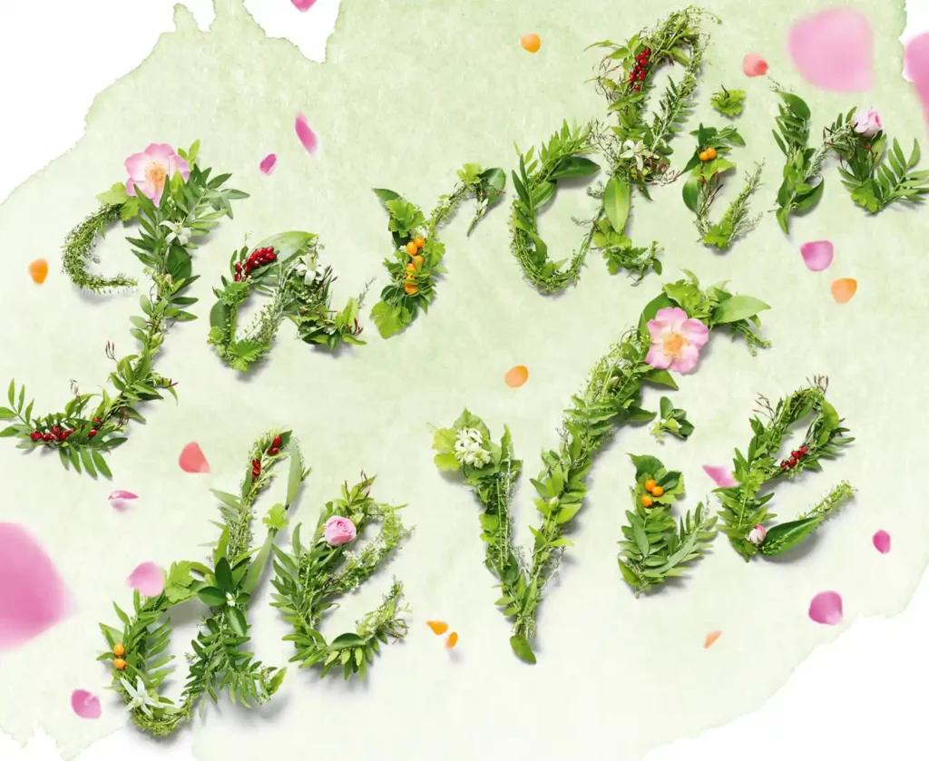 Jardin de Vie. Ein Schriftzug, auf einer hell grünen Aquarellfläche aus Blumen gelegt.