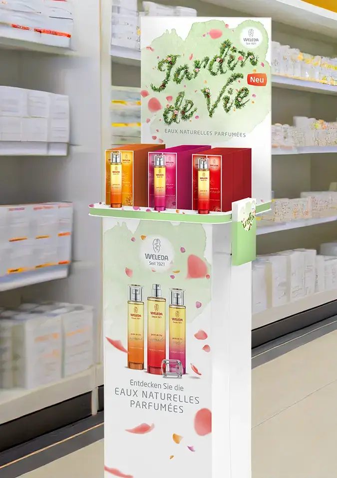 Markenentwicklung internationalen Produkt Launch. Ponit of Sale Aufsteller mit einem aus Blumen gelegten Schriftzug, der Jardin de Vie zeigt. Ein paar Blätter fliegen leicht durch die Luft